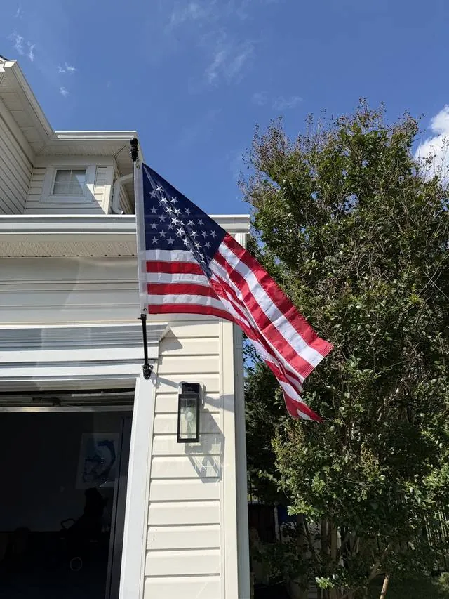An American flag flying from a white clapboard house