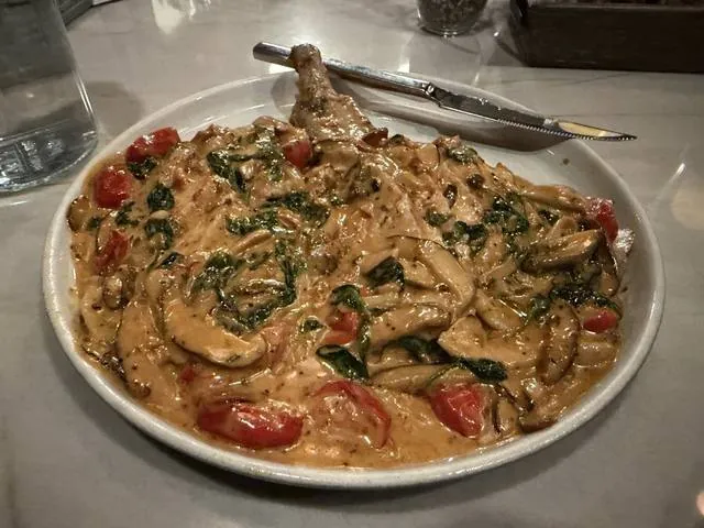 A bowl of pasta with mushrooms, spinach and cherry tomatoes
