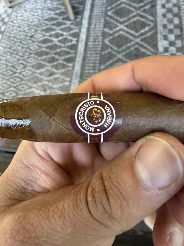 A Montecristo cigar held between two fingers